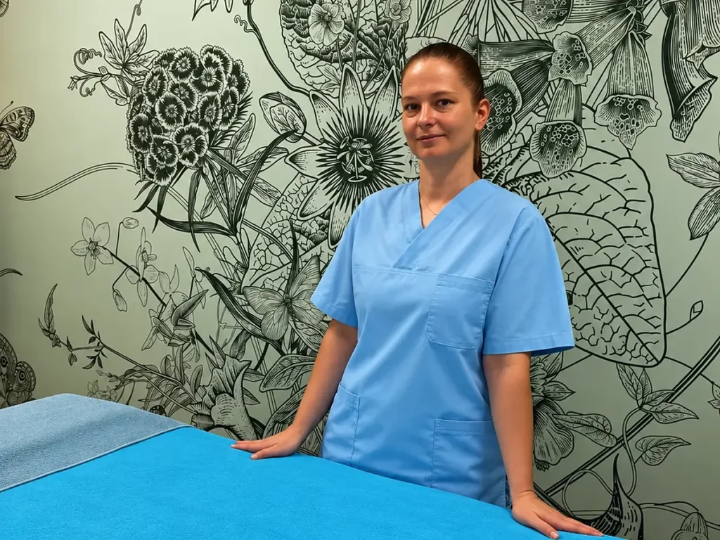 Inna stands beside the prepared treatment bed, ready for a consultation.