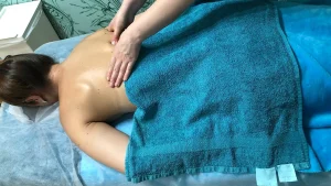 Inna massages the shoulder blades of a client lying face down with a turquoise towel at Faircare in Berlin.