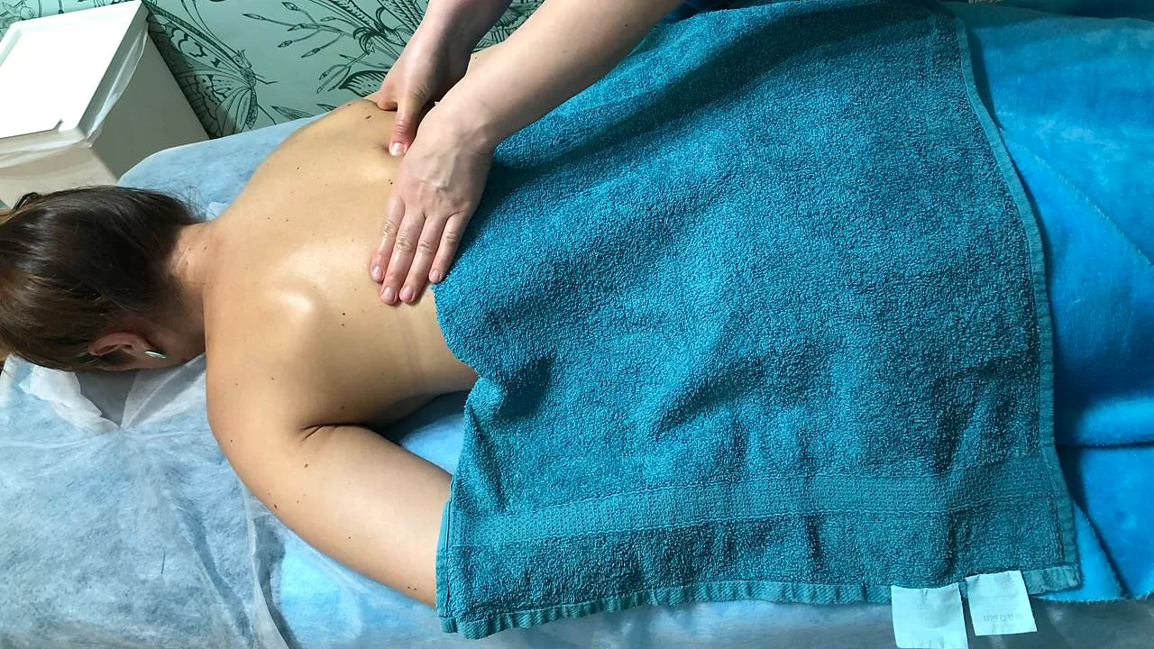 Inna massages the shoulder blades of a client lying face down with a turquoise towel at Faircare in Berlin.